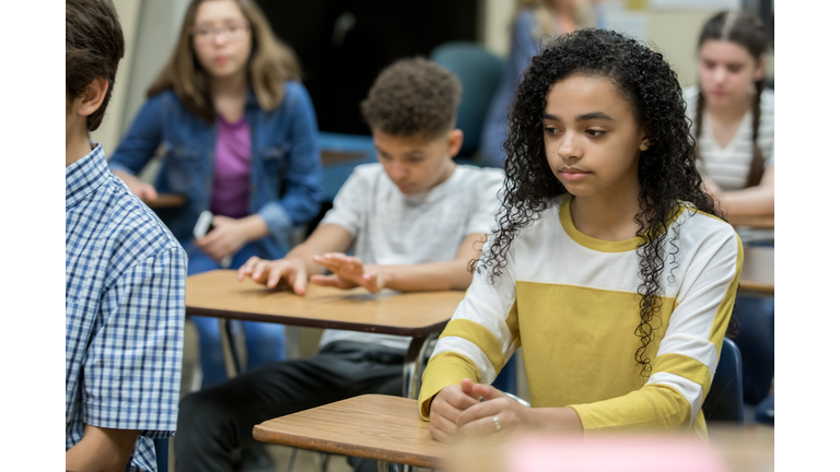 Diverse group of teenage high school students sitting at desks during detention, looking bored and depressed