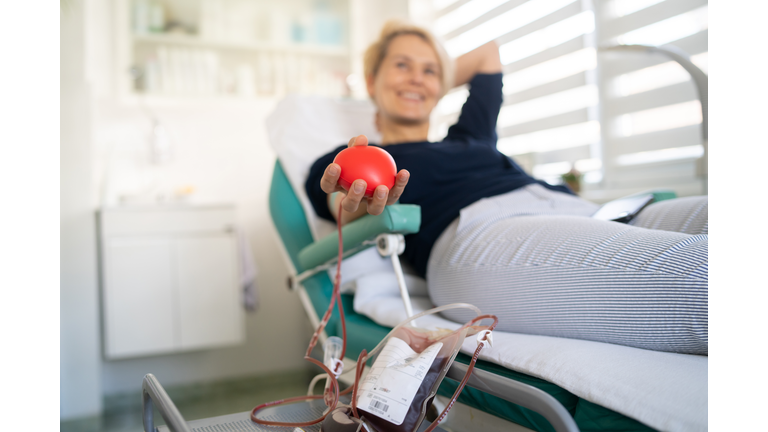 Happy woman is laying down while donating her blood