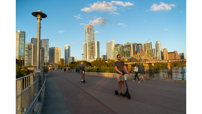 Scooters ride across Pedestrian Bridge in Downtown Austin , Texas