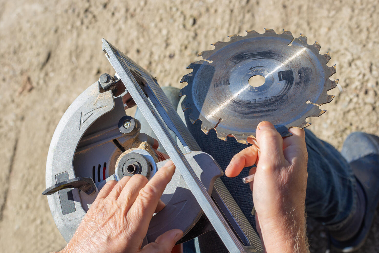 a man replaces a saw blade on a circular miter saw for woodworking