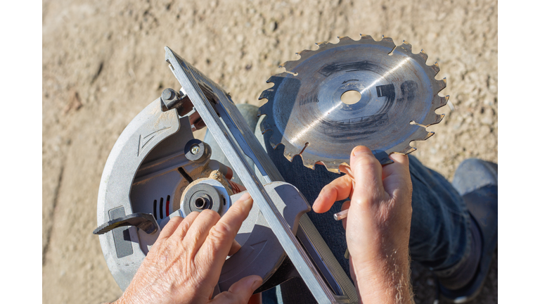 a man replaces a saw blade on a circular miter saw for woodworking