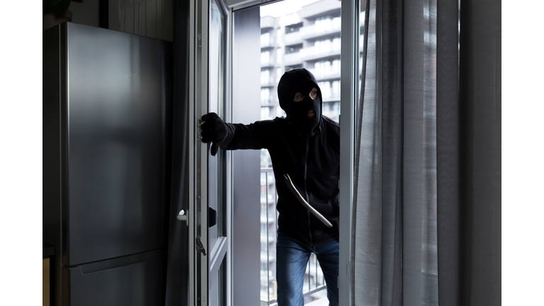 A male thief in a black mask, enters the apartment for robbery, the robber broke the door lock