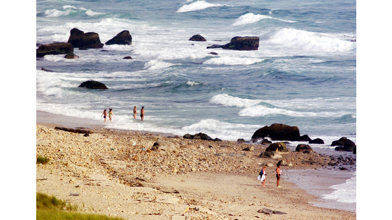 Beachgoers wade into the surf near the search site