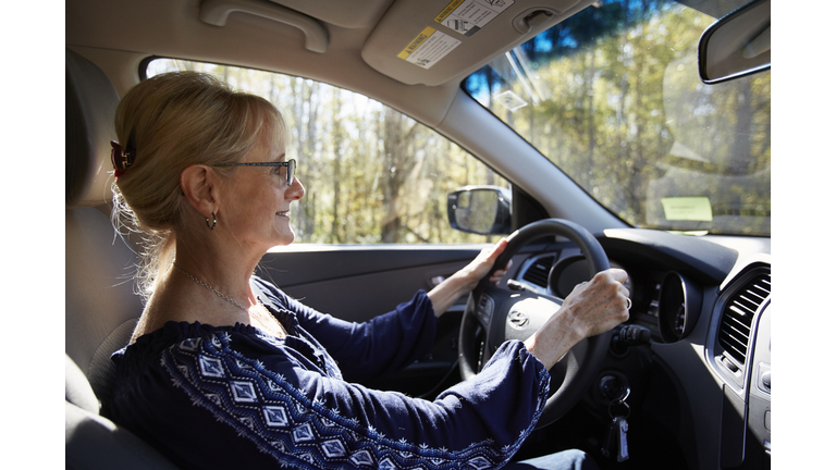 Senior woman with glasses drives car