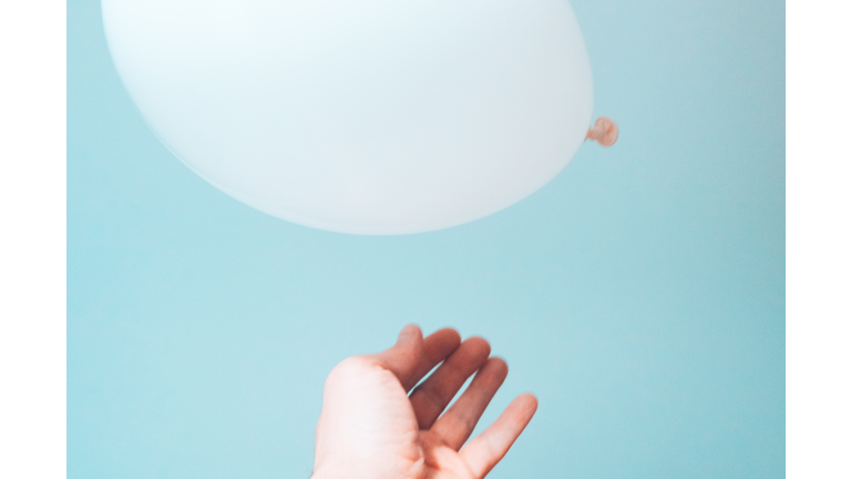 Hand releasing a white balloon into the air