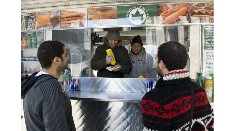 A hot dog vendor serves up a hot dog out