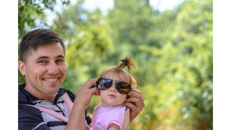 Amazing little girl is playing with sunglasses with her father