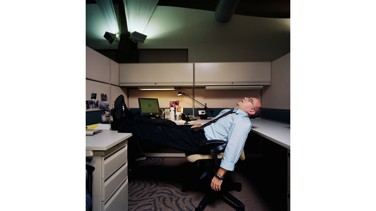Businessman sleeping in work cubicle