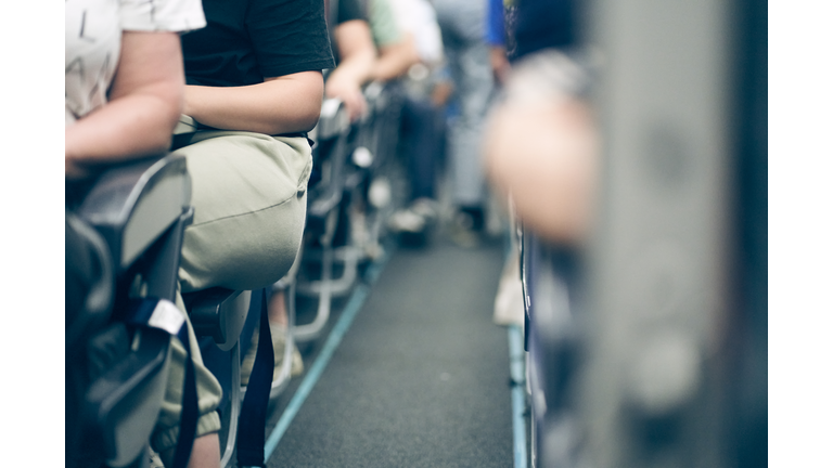 The aisle on the plane, people sitting in their seats, selective focus, lifestyle photo.