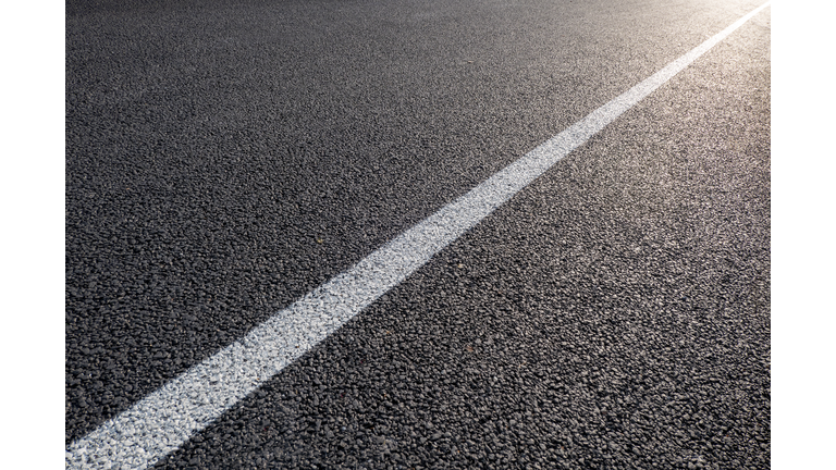 Sunlight illuminates the asphalt pavement