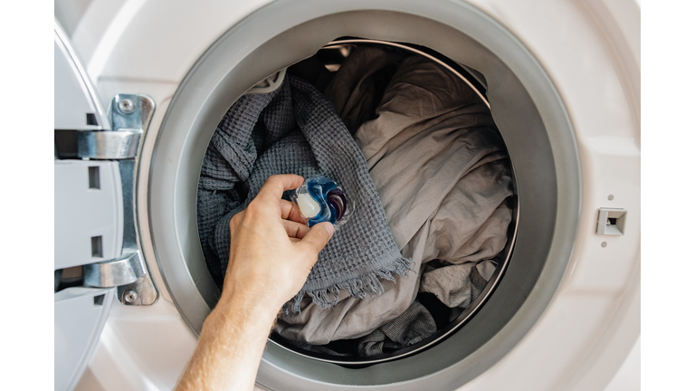 Man putting liquid laundry detergent pod in washing machine