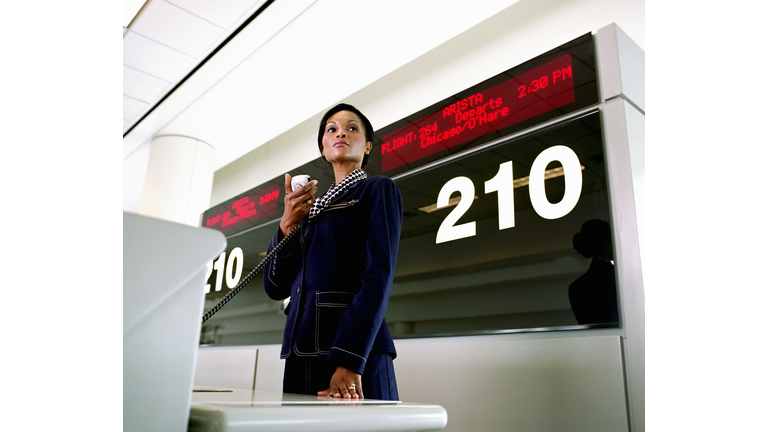 Female airline worker holding public address system microphone