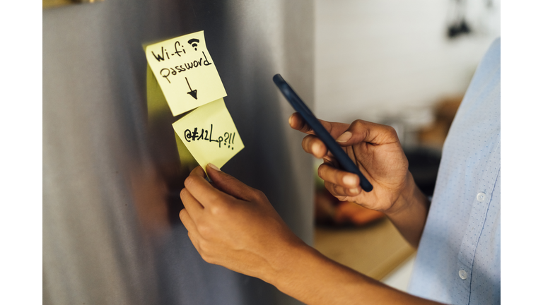 Woman in her kitchen in the morning, posting sticky  notes on the fridge