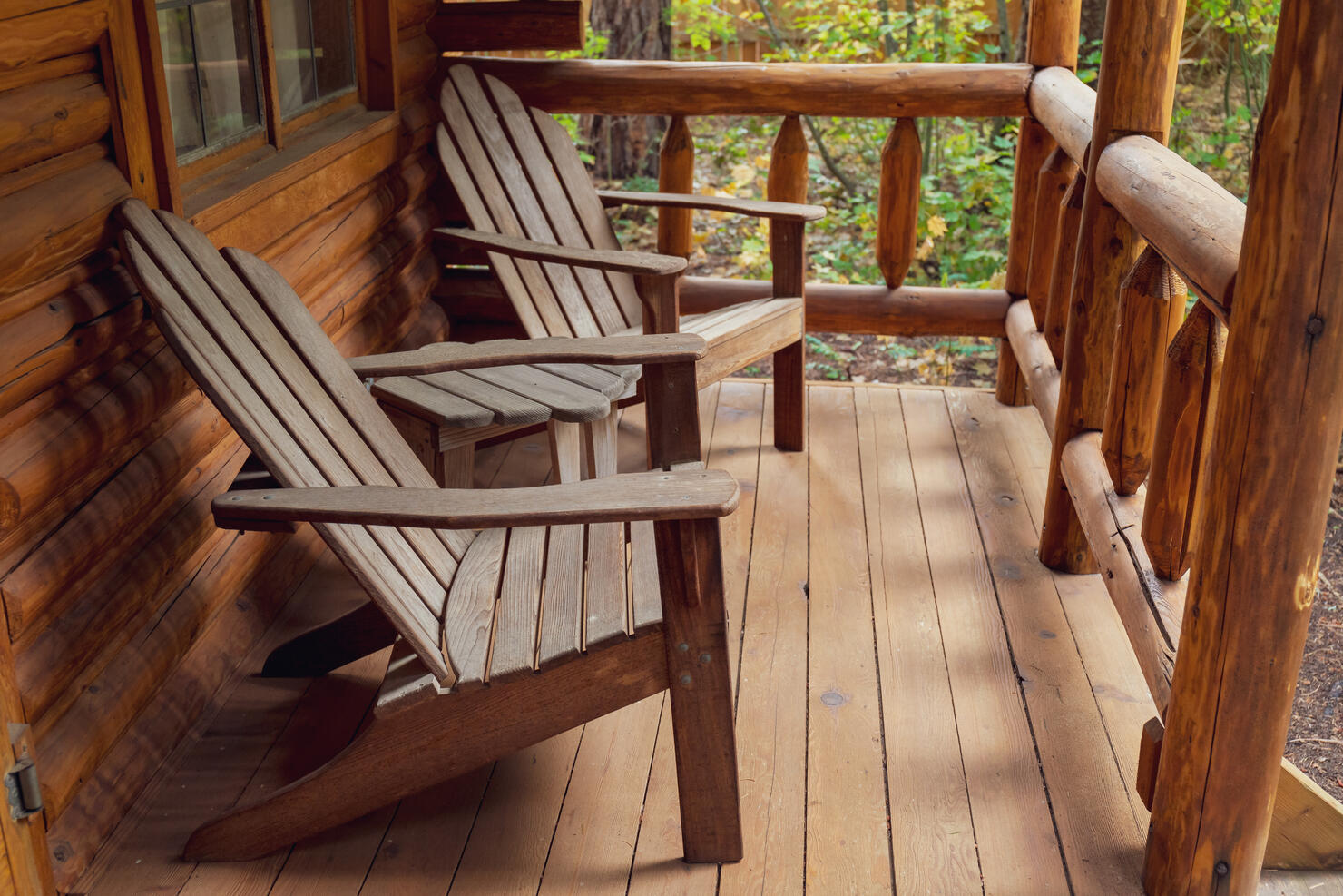 Wooden Adirondack Chairs on Porch of Rustic Log Cabin