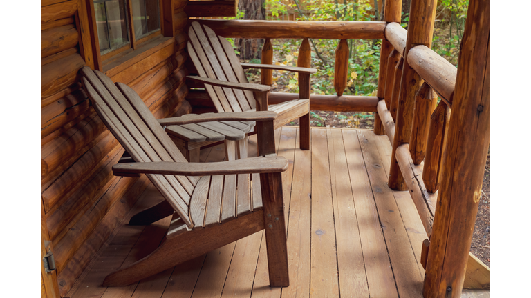 Wooden Adirondack Chairs on Porch of Rustic Log Cabin