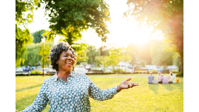 Happy woman with arms out in park