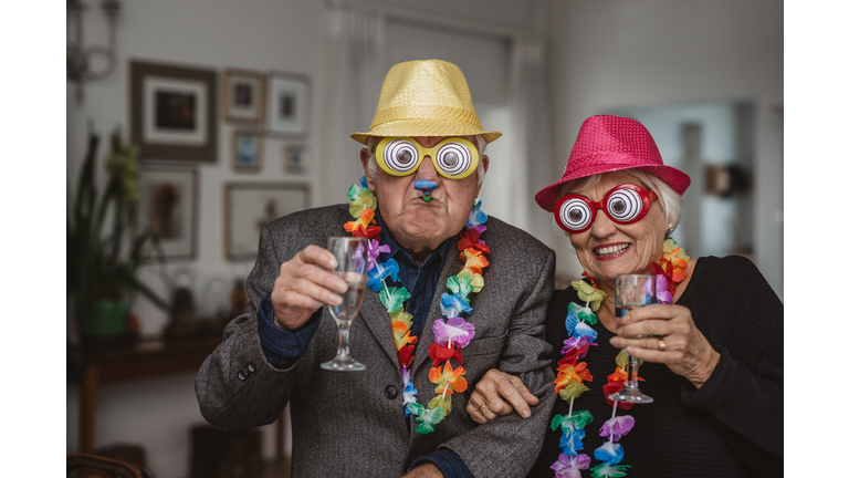 Senior couple drinking and wearing novelty glasses at a party