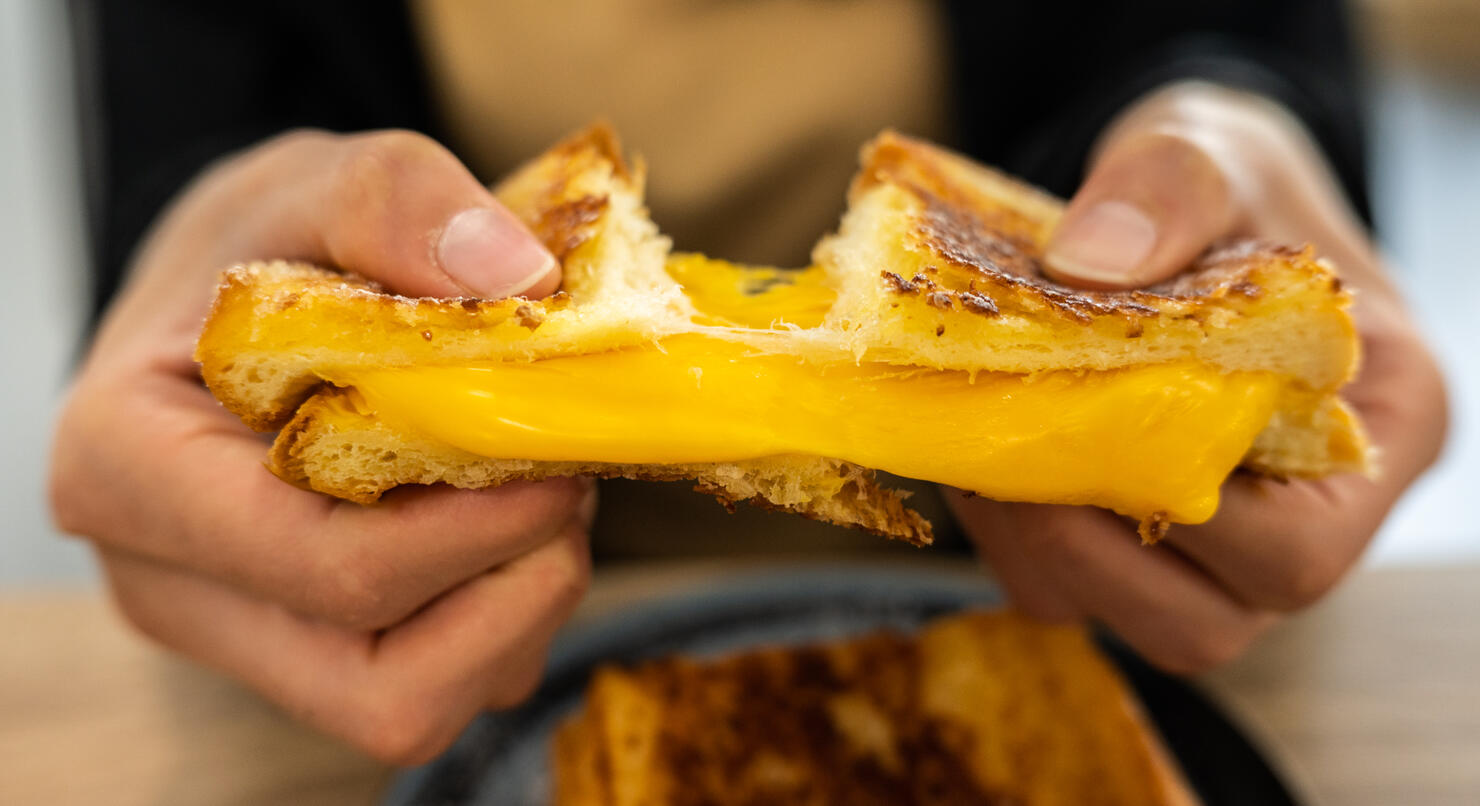 Someone tearing a Cheese Toast before eating.