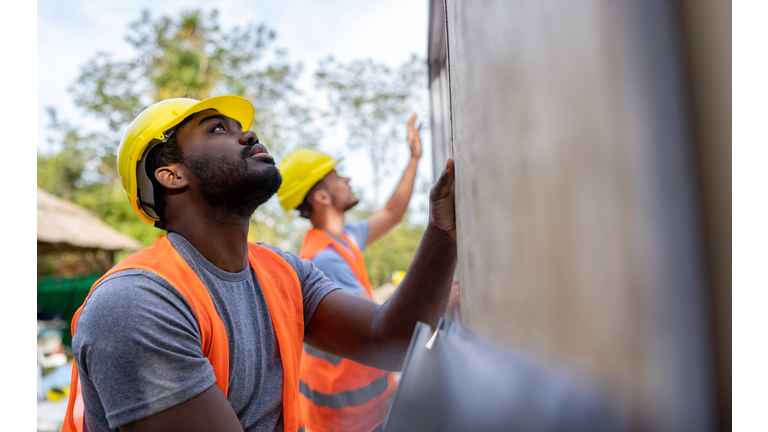 Construction workers installing panels while building a manufactured house