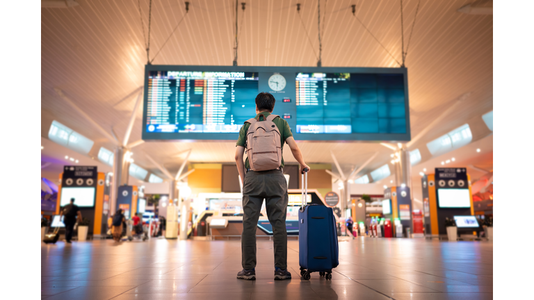 Male tourist looking at arrival and departure board at Kuala Lumpur International Airport