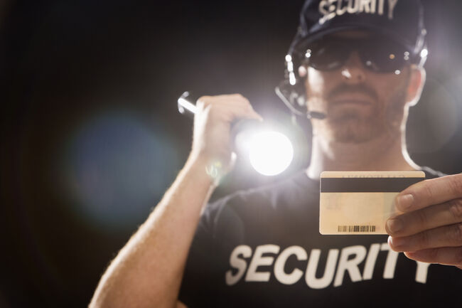 Bouncer checking identification with flashlight