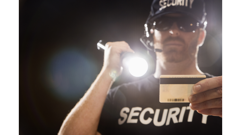 Bouncer checking identification with flashlight