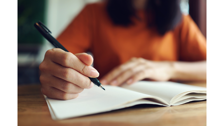 Close up woman hand writing on notebook .