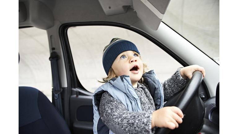 Little boy sitting at steering wheel of car