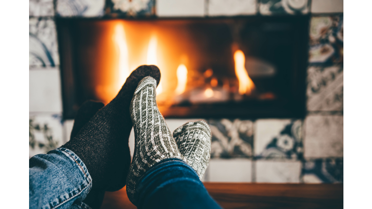 Couple warms their feet by the fireplace.