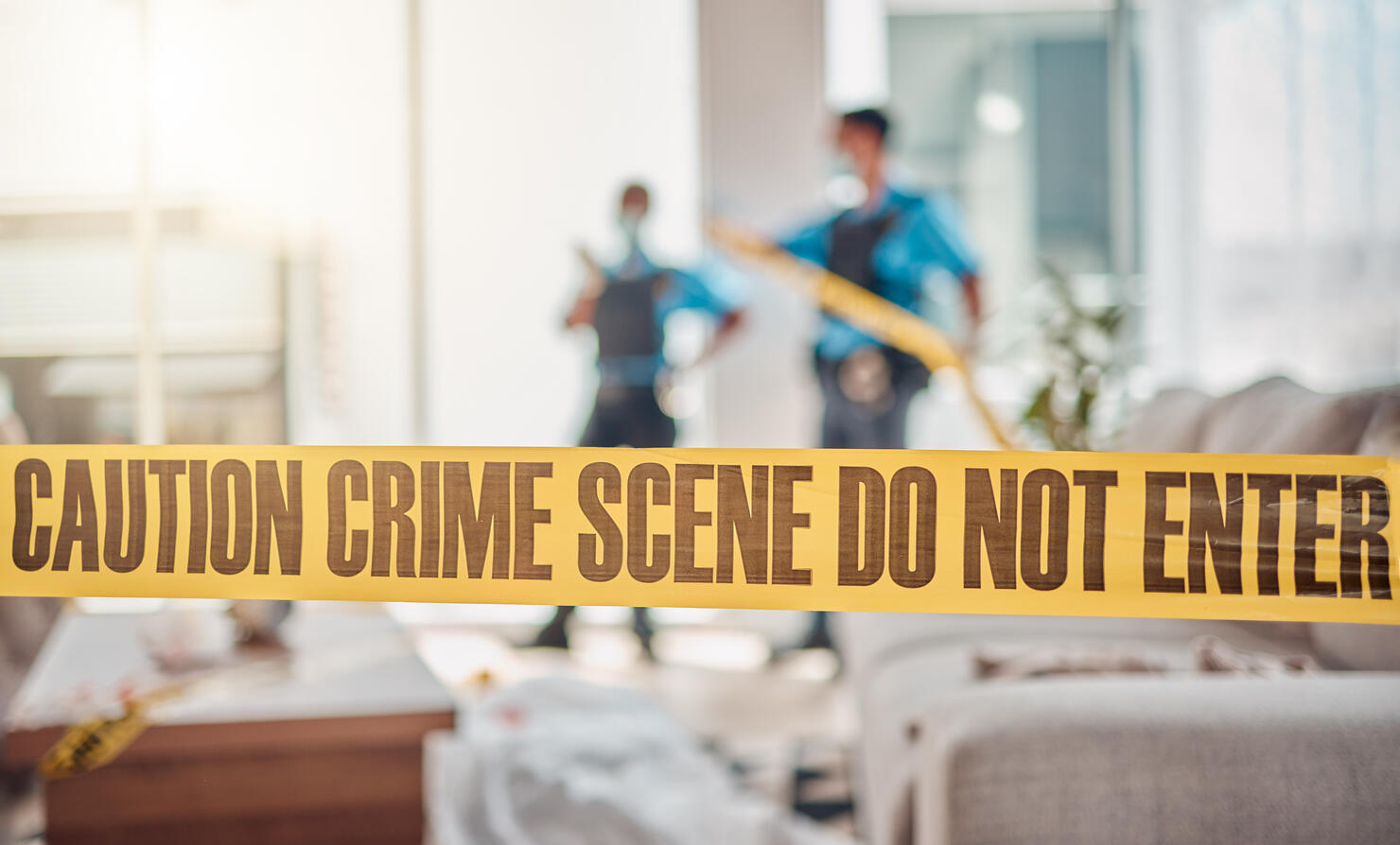 Tape, crime scene and police in house for investigation, inspection and forensic analysis. Law enforcement, safety and security people in living room for criminal, murder and searching for evidence