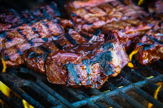 Boneless beef ribs grilling over flames