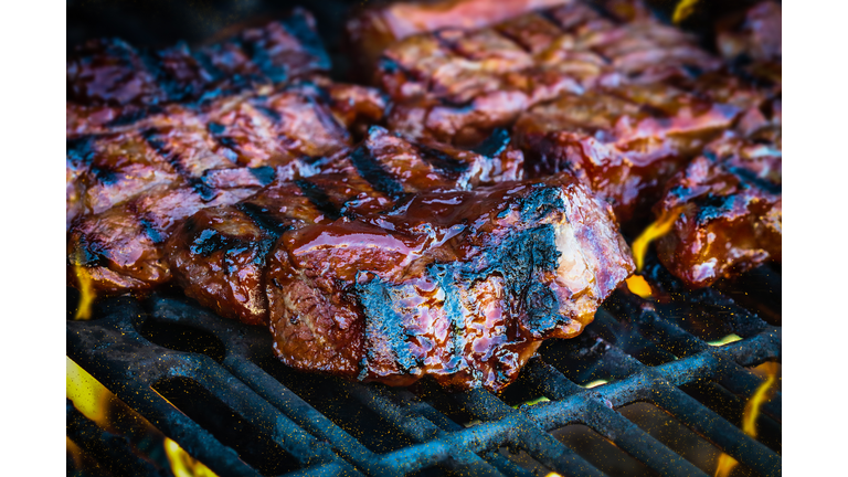 Boneless beef ribs grilling over flames