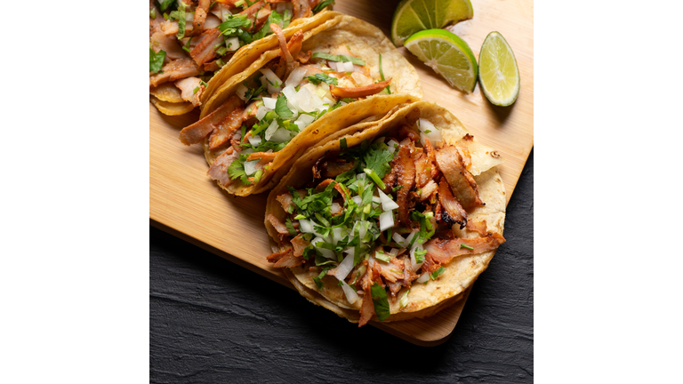 Pork tacos called al pastor with pineapple on dark background. Mexican tacos