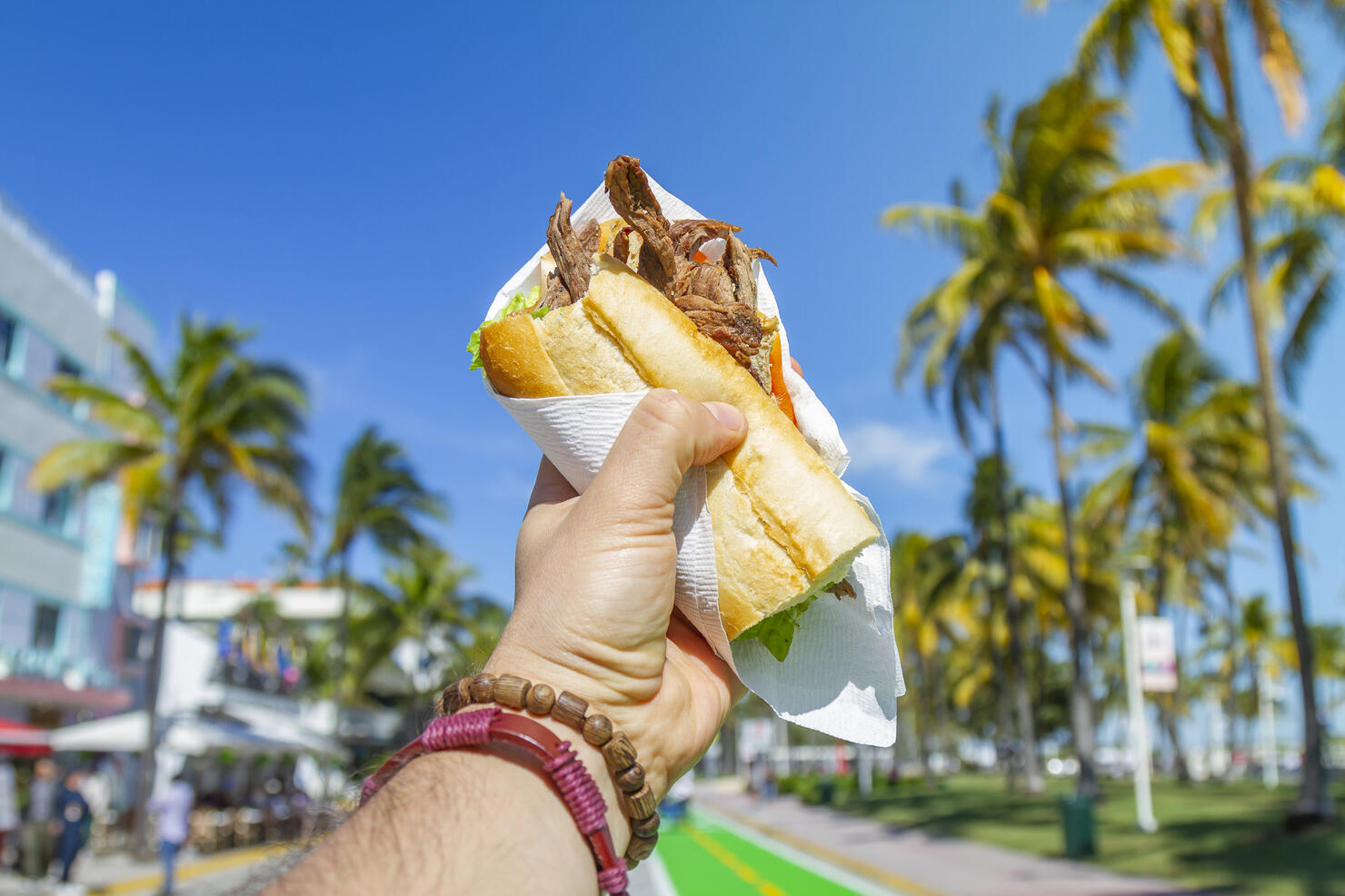 POV Point of view shot of a young travel male enjoying his vacations while eating a cuban sandwich in front of Ocean Drive, South Beach, Miami Beach, Miami, South Florida, United States of America.