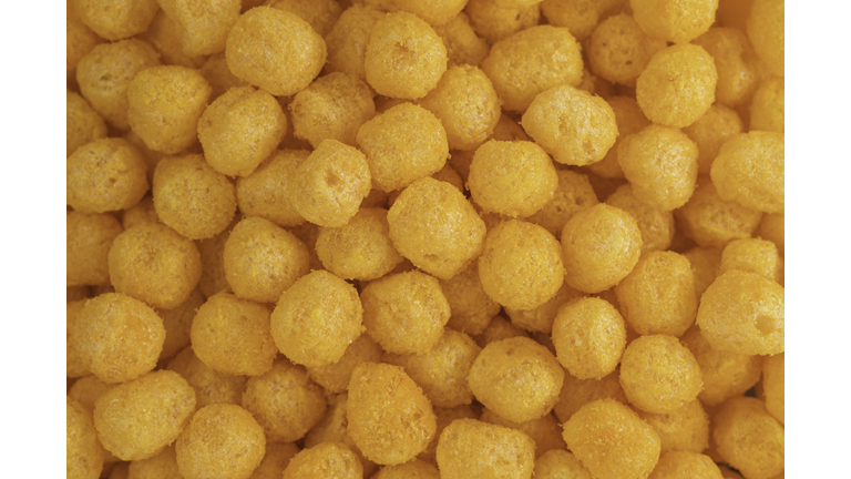 Cheese Corn balls. Texture, Pattern of Cheese flavored snack. Selective focus, food background. Cheese puff. Cinema snacks. Crunchy puffed balls.