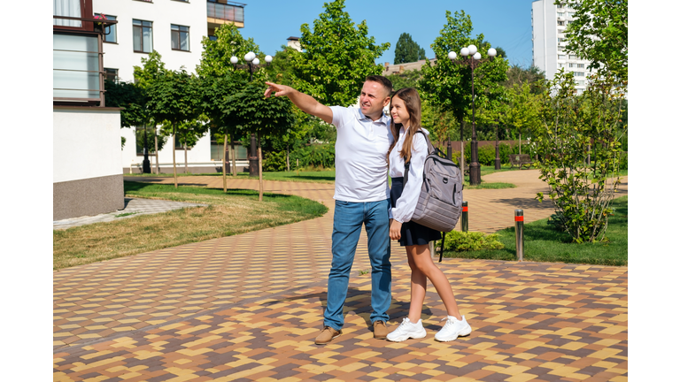 Father proudly hugs his schoolgirl daughter before she goes to school.