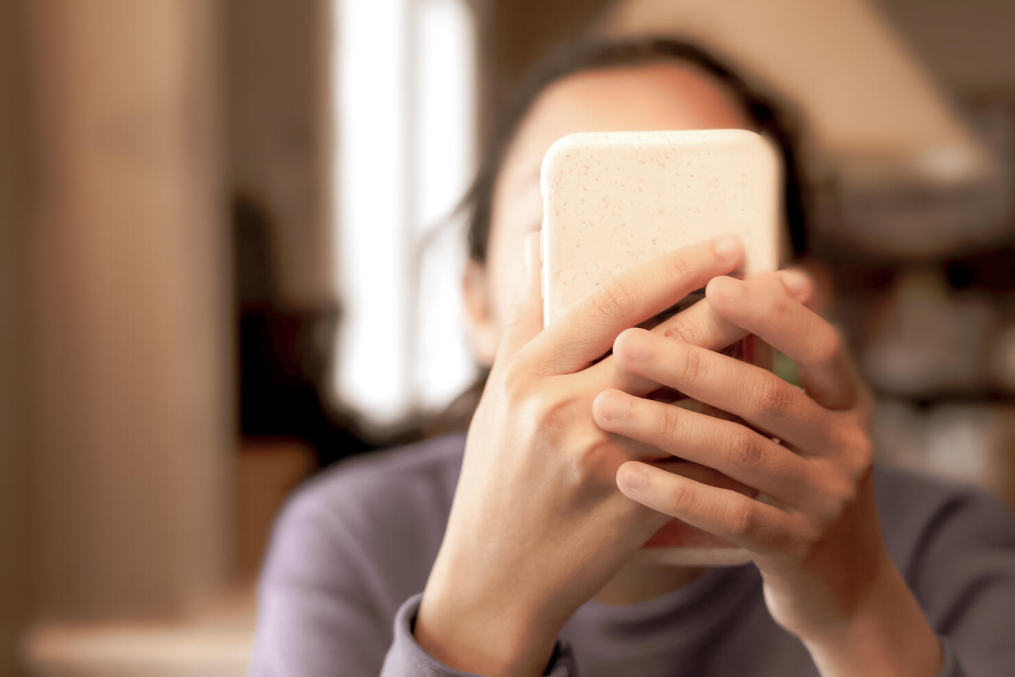 technological progress or social media problem: young mixed-race female holding smart phone up to face