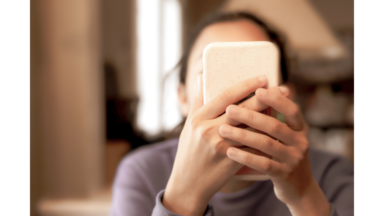 technological progress or social media problem: young mixed-race female holding smart phone up to face