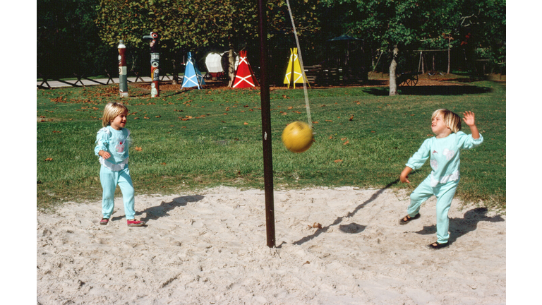 Twin toddlers playing punchball on a playground