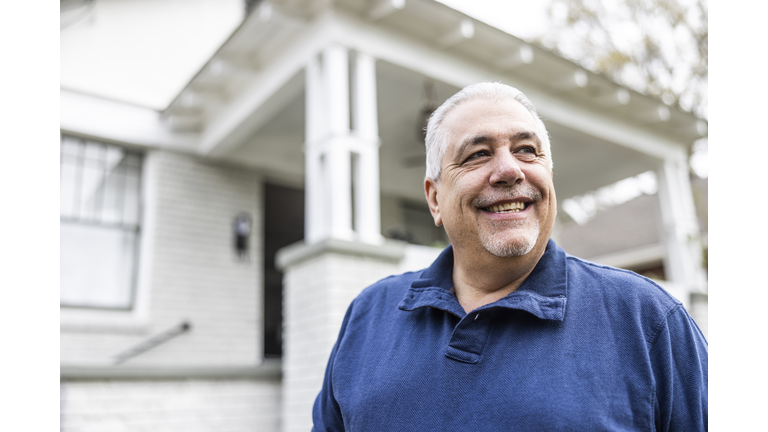 Portrait of senior man in front of suburban home