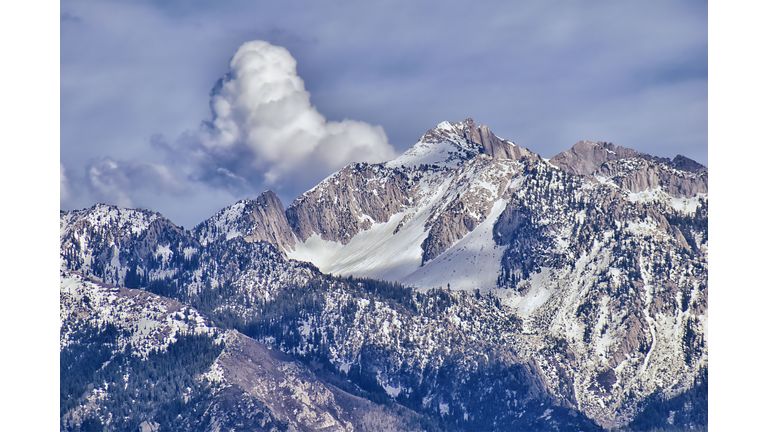 Panoramic view of Wasatch Front Rocky Mountain, highlighting Lone Peak and Thunder Mountain from the Great Salt Lake Valley in early spring with melting snow, pine trees, scrub oak and quaking aspen in Utah.