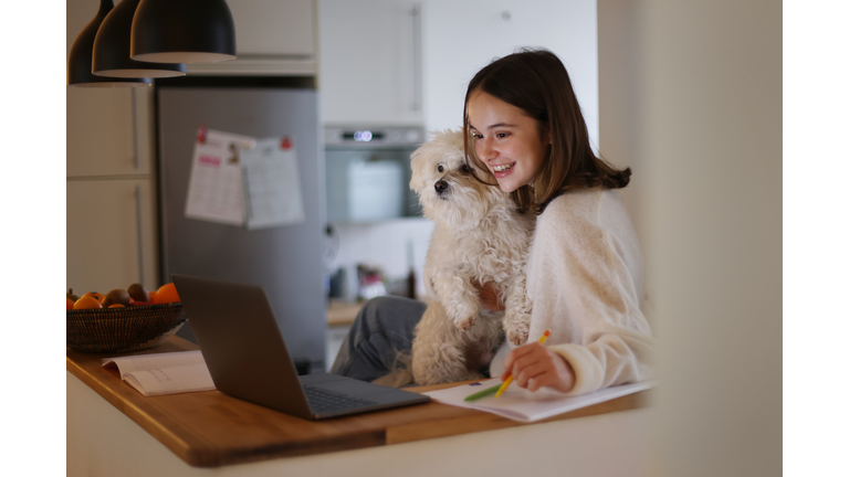 A 15 years old girl and her dog attending online school classes from home