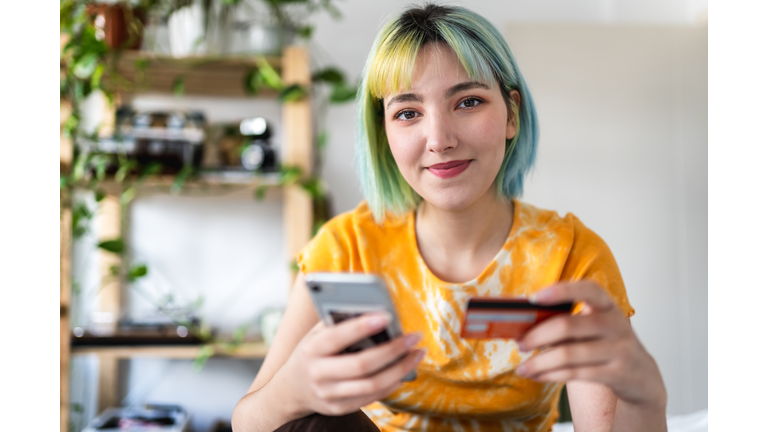 Young woman with colored hair is shopping online with a credit card