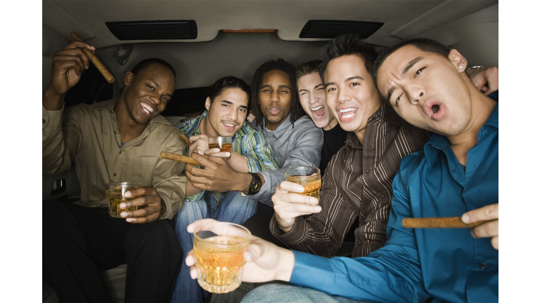 Multi-ethnic men celebrating in limousine