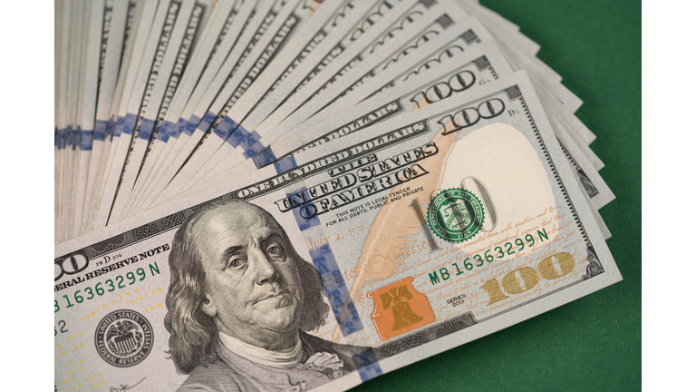 Closeup view of stack of one hundred dollars banknotes on dark green background. Cash money. Financial growth and business concept