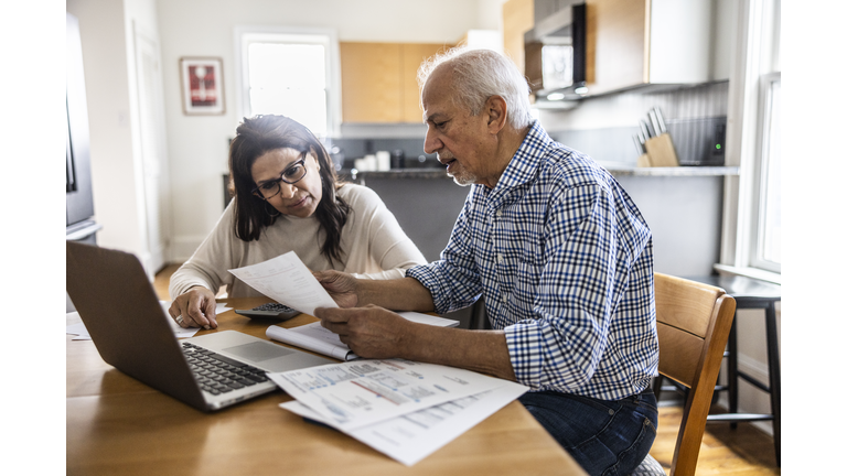 Senior couple paying bills at kitchen table