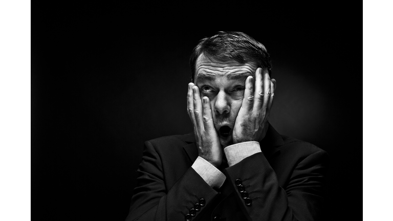 Mature man gesturing against black background, close up