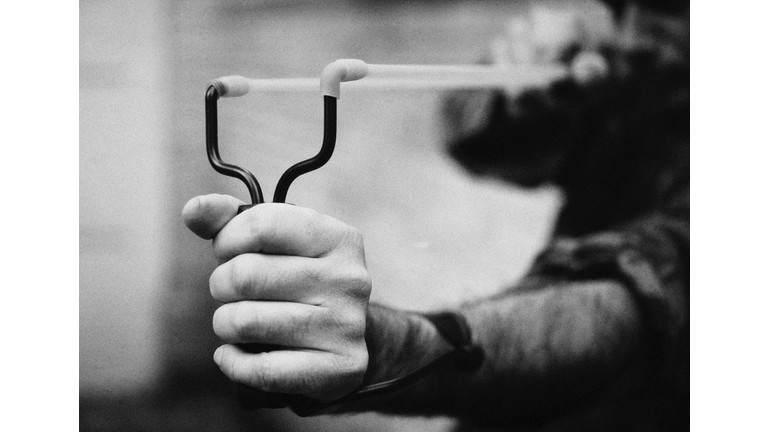 Hands holding sling shot, close-up, b&w