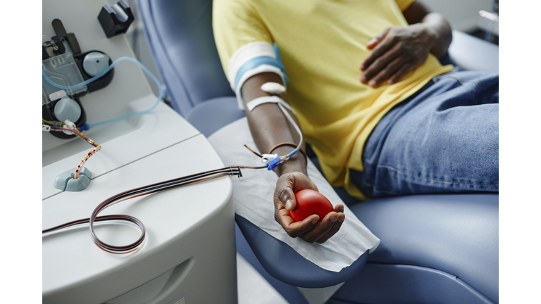 Man holding soft ball and donating blood at center