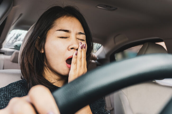 Tired sleepy Asian woman yawning during driving car